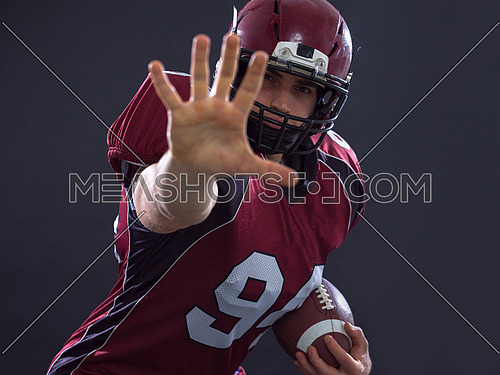 Portrait of American football player pointing against gray background
