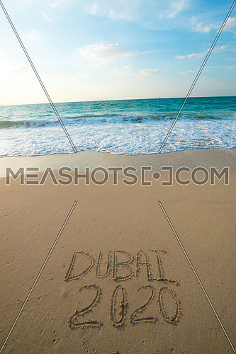 in the picture at the beach  written on the sand Dubai 2020