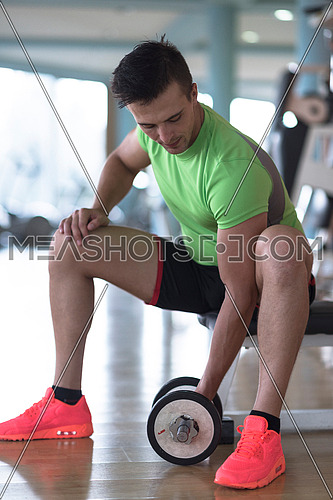 young handsome man working out with dumbbells in a fitness gym