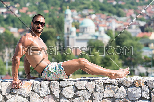 Smiling Athlete With Naked Torso Sitting And Resting On Rocks