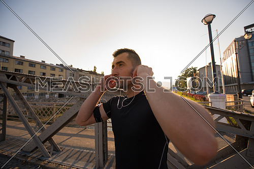 portrait of a young sporty jogging man at sunny morning in the city