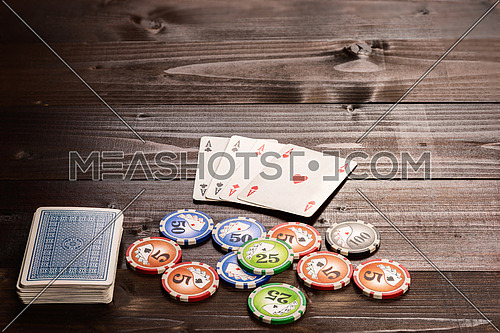 Four aces and chips, vintage poker game playing cards on a wood table