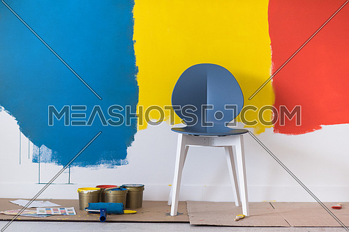 empty chair and equipment for painting in front of colorful wall in the background