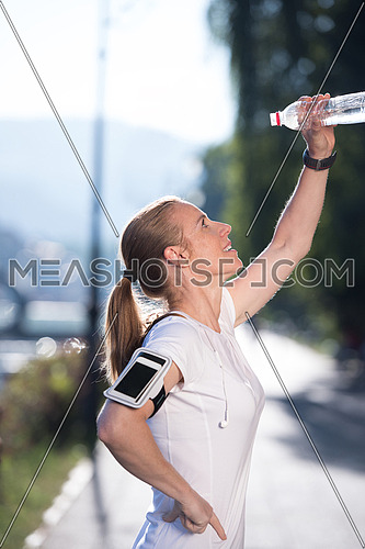 young woman drinking a water after mornig jogging workout  city  sunrise in background