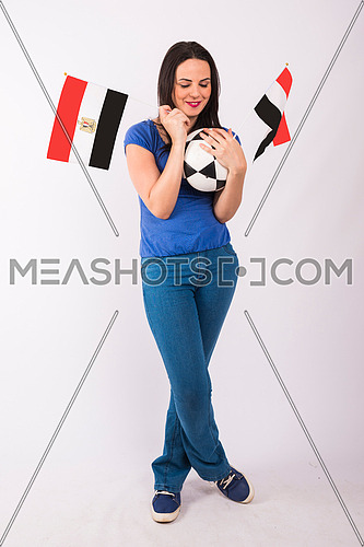 Young lady standing and holding two small egyptian flags, and ball on white background.