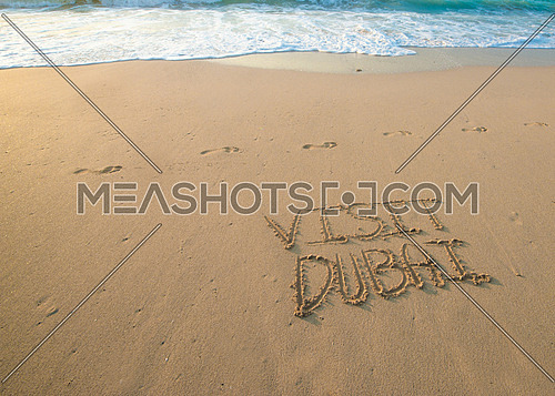 in the picture at the beach  written on the sand Visit Dubai