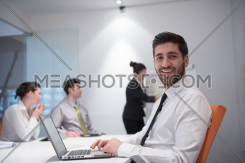 portrait of young modern arab business man with beard at office meeting room,   group of  business people  on brainstorming and  making plans and projects on white flip board in  background