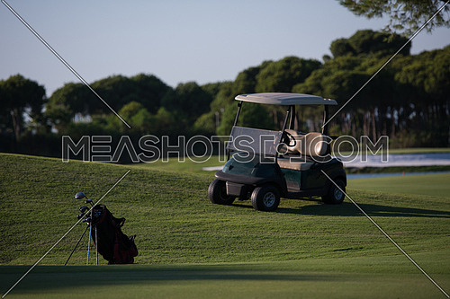 golf bag on course with  club and ball in front at beautiful sunrise