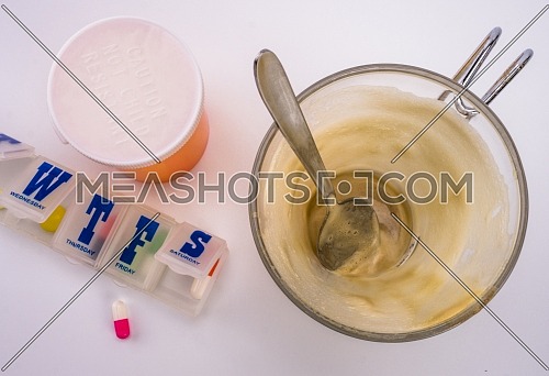 Medication during breakfast, cup of coffee next to a pillbox, conceptual image, horizontal composition