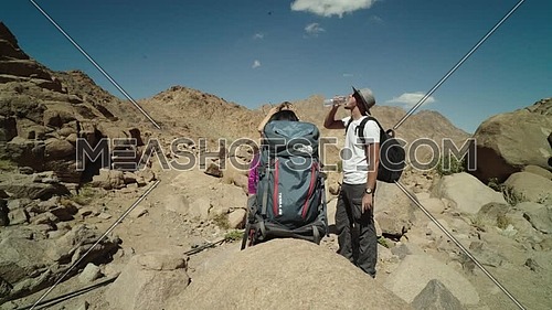 Follow shot for a group of tourists wearing backpacks standing and talking while exploring Sinai Mountain for wadi Freij at day.