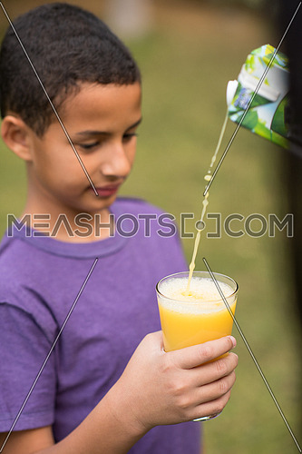 a  middle east boy with a glass hand cheerfully waiting healthy natural beverage outdoors