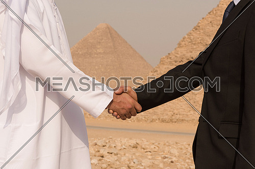 successful arab business people shaking hands over a deal with Egyptian giza pyramids in backgronud