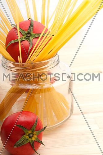 fresh tomato and raw spaghetti pasta over pine wood table