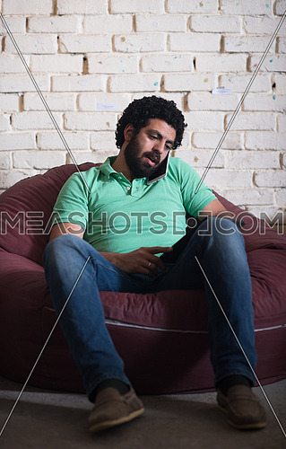 casual middle eastern young businessman talking on the phone, and tablet used in modern stylish office