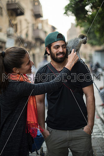 two young middle eastern tourists enjoy playing with a monkey in the city