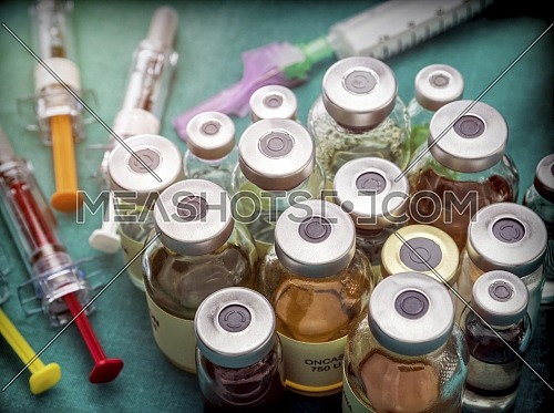 Different types of vials with medication along some syringes in a hospital, conceptual image