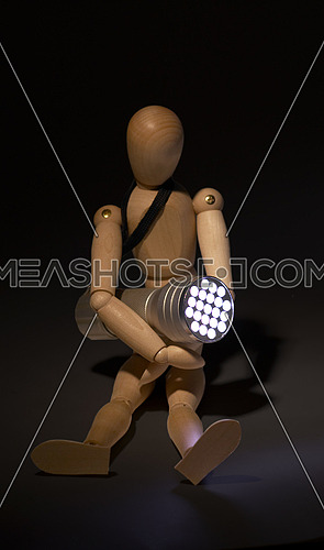 wood mannequin and flashlight glowing on the dark over black background