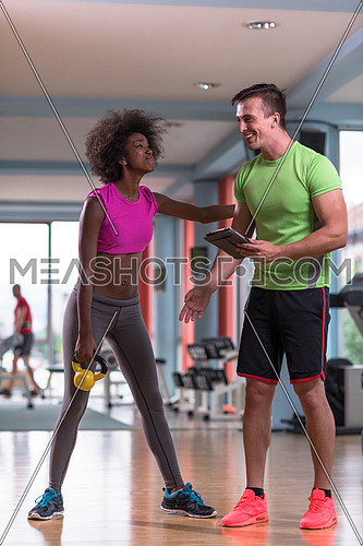 healthy young couple in crossfit gym weights workout with personal trainer