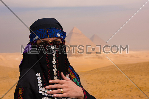egyptian woman in traditional clothes in front of ancient giza pyramids