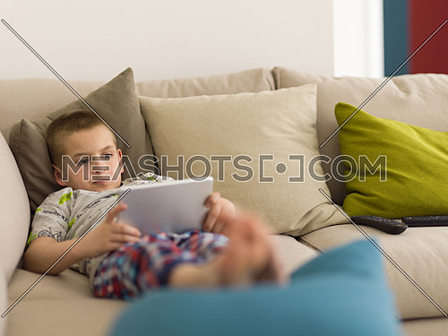 little boy playing video games on tablet computer at home