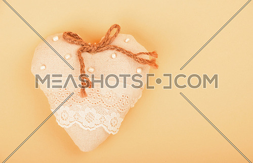 Valentine template, handmade beige toy textile lace heart with burlap jute bow, beads and copy space on paper background
