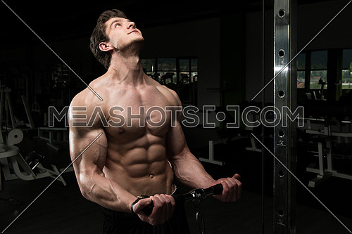 Young Muscular Fitness Bodybuilder Doing Heavy Weight Exercise For Biceps On Machine With Cable In The Gym