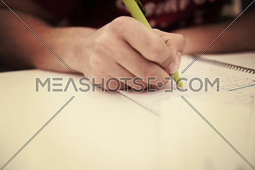 Close up of a student hand underlining a document on a desk at school classroom
