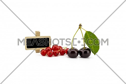 Two ripe cherries with a green leaf and a bunch of red currants and small signboard isolated on a white background