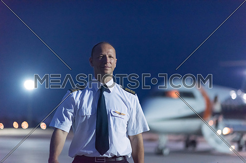 Portrait of a young middle eastern successful pilot in front of private jet one summer evening