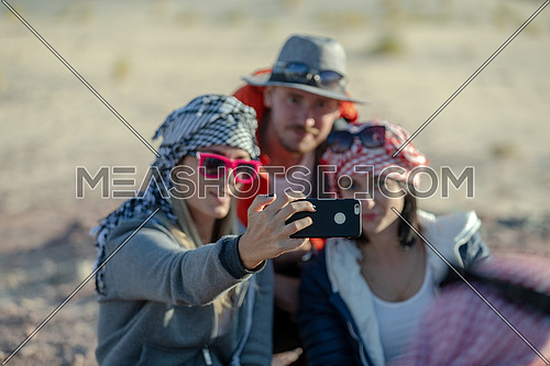 mid shot for group of tourists wearing bedouin traditions headscarf and taking selfies at Ain hodouda in Sinai at day