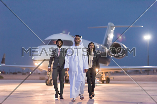 young successful businessmen walking with their Arab business partner in front of private airplane