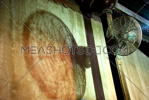 a vintage looking fan with shadow on the wall