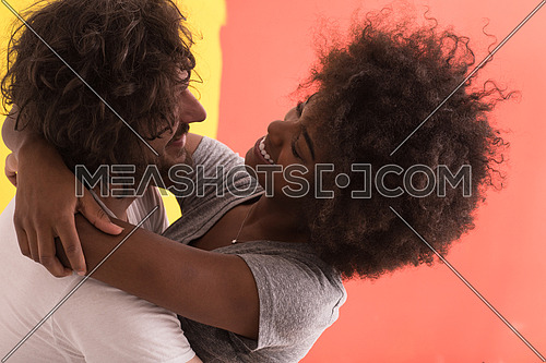 Young happy multiethnic couple hugging while they painting a wall in their new home