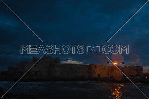 Long Shot outside Citadel of Qaitbay shows sea waves at Cloudy day to night