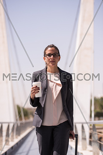 young businesswoman with travel bag and fresh morning coffee walking to catch the plain at  airport