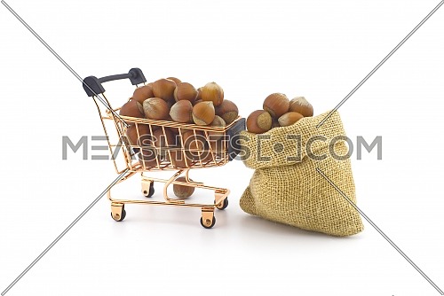 Shopping cart and small hessian bag filled with whole ripe hazelnuts isolated on white background