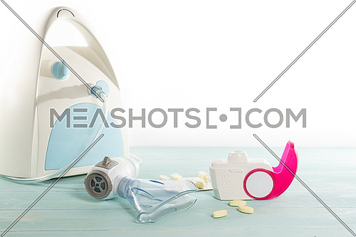 Set of asthma inhaler, anti-allergy pills and aerosol machine with inhaler mask,concept asthma and treatment on green background,copy space.