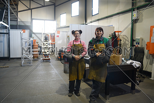 portrait of two welders holding welding masks in their hands and preparing for hard work in a factory. High quality photo