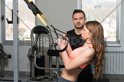 Personal Trainer Showing Young Woman How To Train With Trx Fitness Straps In A Health And Fitness Concept
