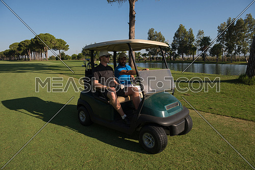 golf players driving cart at course on beautiful morning sunrise. friends together have fun and relax on vacation.