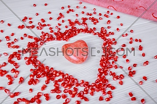 Heart symbol made from fresh organic pomegranate seeds on white background