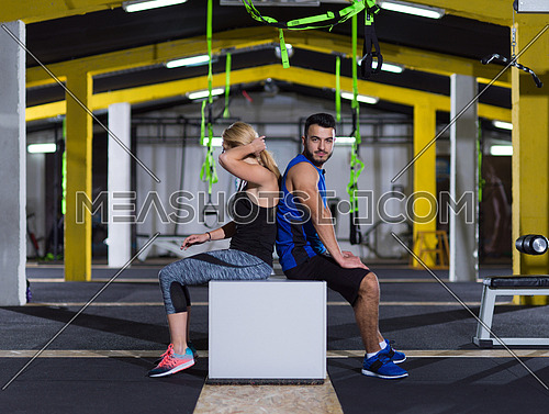 portrait of young healthy athletic people training jumping on fit box at crossfitness gym