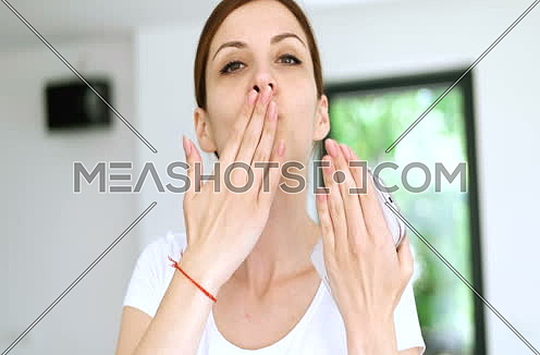 woman sending kiss to camera in modern apartment