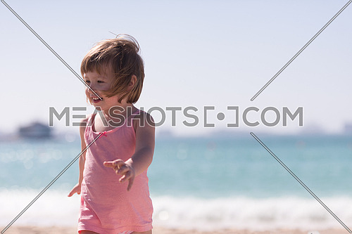 happy little girl at the seaside in the summer.Adorable little girl at beach during summer vacation. Happy baby by the sea or ocean