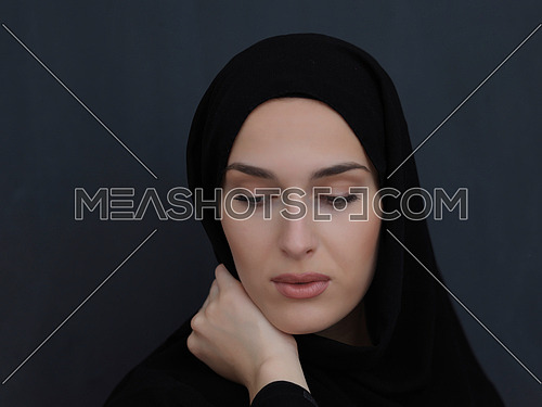 Portrait of modern young muslim woman in black abaya. Arab girl wearing traditional clothes and posing in front of black chalkboard. Representing modern and rich arabic lifestyle