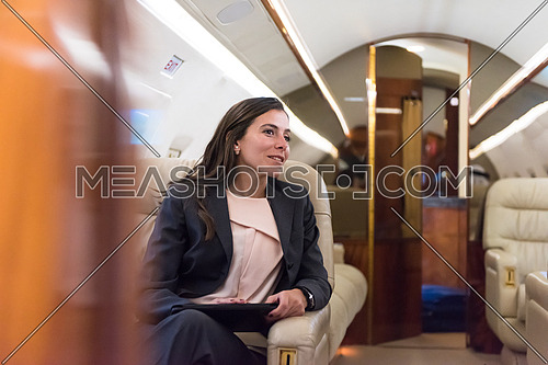 Portrait of a young middle eastern successful businesswoman sitting on a private jet with a tablet in hands