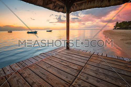 Perspective view of a wooden pier that create two amazing frame at sunset,tropical beach in Mauritus island