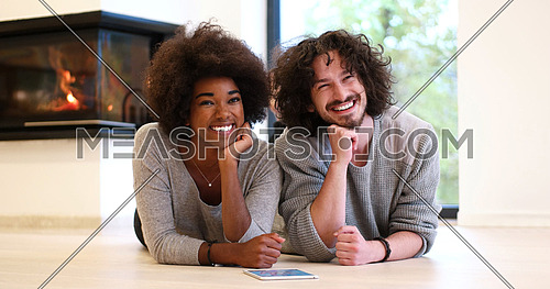 beautiful young multiethnic couple lying on the floor of their luxury home in front of fireplace at autumn day