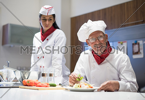 older middle eastern chef and his assistant enjoy preparing meals in the kitchen