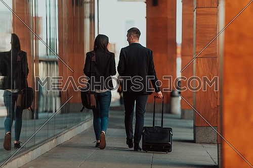 Businessman and businesswoman talking and holding luggage traveling on a business trip, carrying fresh coffee in their hands. Business concept. High-quality photo